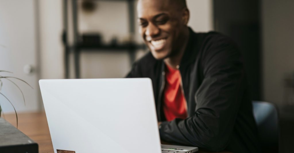 a man smiling at his laptop